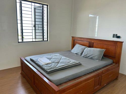 a bed with a wooden frame and a window at Hòa Homestay 