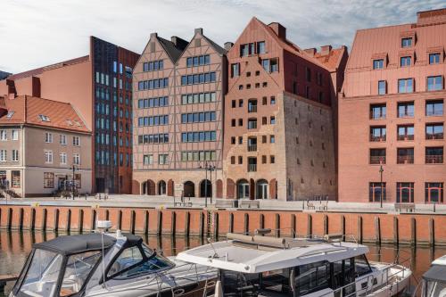 a boat docked in the water in front of buildings at Casa Blush - LoftAffair Spa Collection in Gdańsk