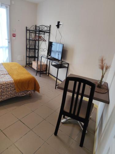 une chambre avec une chaise, une table et une télévision dans l'établissement Studio de L'Estuaire, à Saint-Seurin-de-Cursac