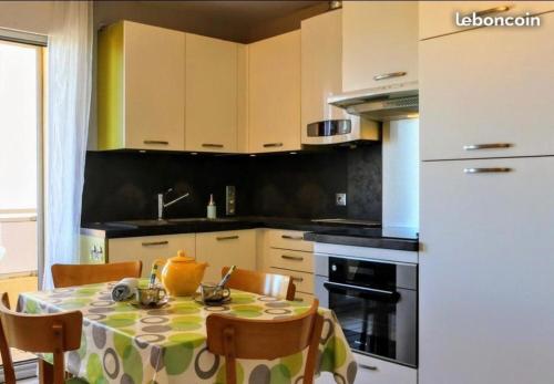 une cuisine avec une table et des chaises et une cuisine avec des armoires blanches dans l'établissement Beau 2 pièces FRONT DE MER, proche commerces, à Canet