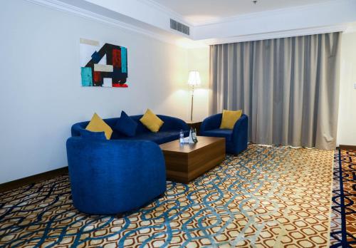 a hotel room with blue couches and a coffee table at فندق اهلا Hola Hotel in Al Jubail