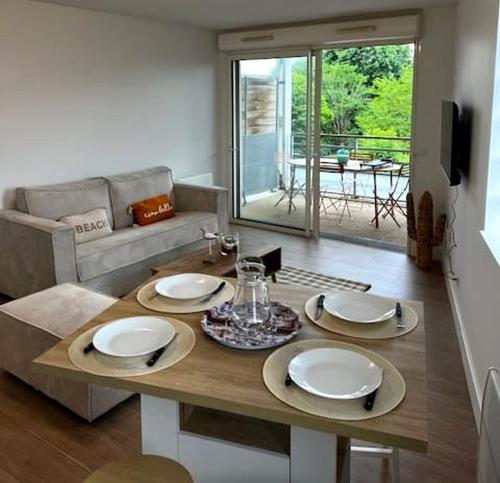 ein Wohnzimmer mit Tisch und Couch in der Unterkunft Le Petit Bassin in La Teste-de-Buch