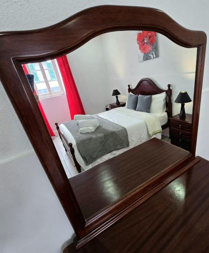 a bedroom with a large wooden bed and a mirror at The Cedar Tree House in Sete Cidades