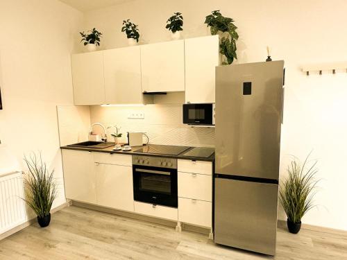 uma cozinha com armários brancos e um frigorífico de aço inoxidável em VIBE S32 Apartman,AC,Free Parking em Székesfehérvár