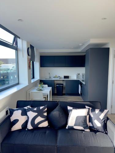a living room with a black couch and a kitchen at Modern & Stylish 1-Bed Apartment near Old Trafford and Central Manchester in Manchester