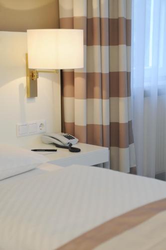 a lamp on a table next to a bed at relexa hotel Schatten Stuttgart in Stuttgart