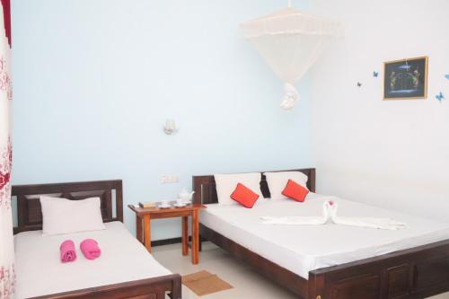 two beds in a room with pink slippers on them at La Casa Safari Resort in Udawalawe