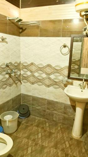 a bathroom with a sink and a toilet and a mirror at Hotel Sandalwood in Amritsar