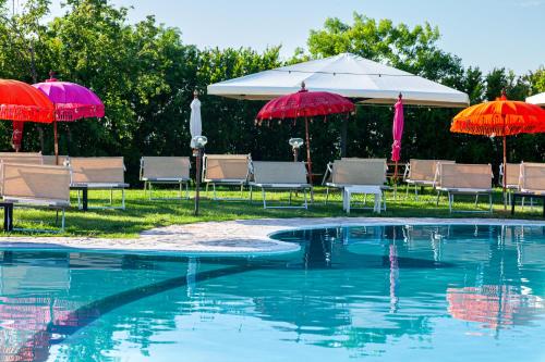 a swimming pool with umbrellas and chairs and a pool at Il Podere Del Germano Reale in Coriano