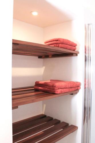 un placard avec des étagères en bois et des serviettes rouges dans l'établissement Au Coeur du marché - Hyper centre Dijon - Terrasse, à Dijon