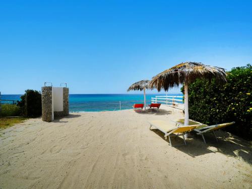 two chairs and an umbrella on a beach at Marinella Beach Apartments - On The Beach - Private Free Parking in Capo Vaticano