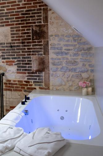 a white bath tub in a room with a brick wall at Les Écuries de Juranville in Bourges