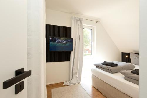 a white room with a bed and a tv on a wall at Seegasse in Göhren-Lebbin
