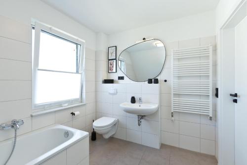 a white bathroom with a sink toilet and a mirror at Seegasse in Göhren-Lebbin