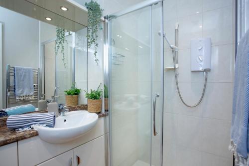 a bathroom with a sink and a glass shower at Dairy Cottage in Seaton