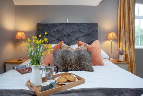 a tray with cookies and flowers on a bed at Dairy Cottage in Seaton