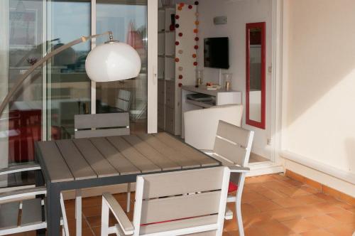 une table à manger avec des chaises blanches et une lampe dans l'établissement Appartement Village Naturiste Hermès, au Cap d'Agde