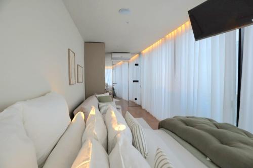 a living room with white furniture and a large window at Villa La Finca - Gerês in Vieira do Minho