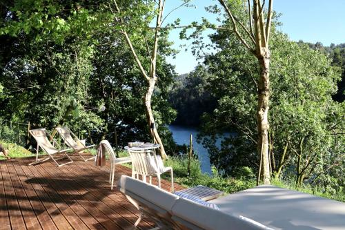 a deck with chairs and a table with a view of a river at Villa La Finca - Gerês in Vieira do Minho