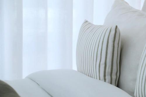 a white couch with a pillow sitting next to a window at Villa La Finca - Gerês in Vieira do Minho
