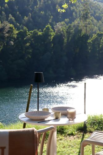 a white table with two dishes on it next to a river at Villa La Finca - Gerês in Vieira do Minho
