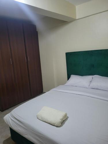 a bedroom with a white bed and wooden cabinets at Baylynn Homes in Homa Bay