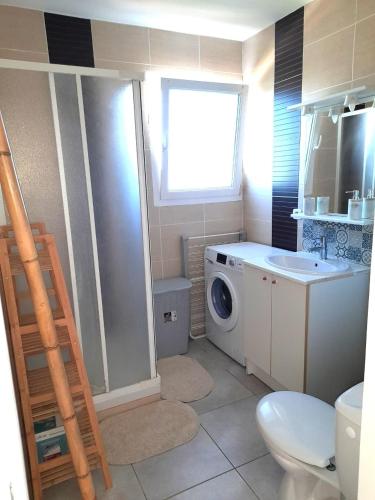une salle de bain avec une machine à laver et un lavabo dans l'établissement Appartement cosy et terrasse spacieuse, à Vic-la-Gardiole