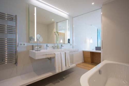 a white bathroom with a sink and a tub and a mirror at Hipotels Playa de Palma Palace&Spa in Playa de Palma