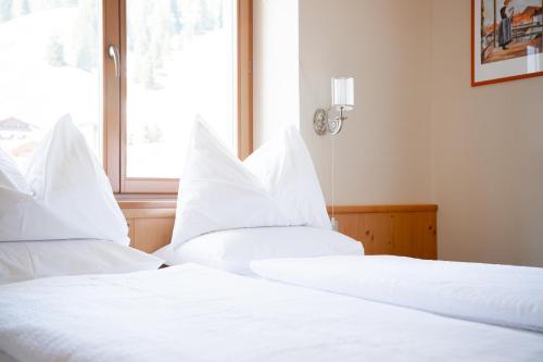 two white beds in a room with a window at Hotel Euròpa Dolomites in Selva di Val Gardena