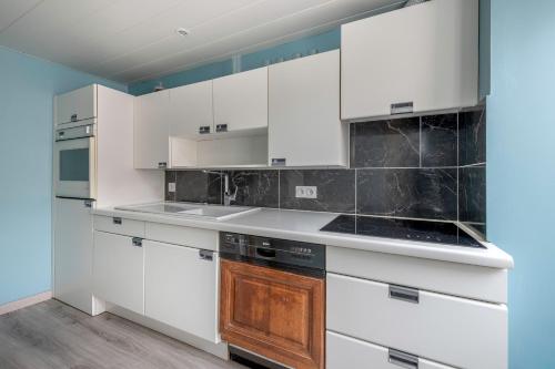une cuisine avec des armoires blanches et des appareils noirs dans l'établissement Maison pour 5 à 350m de la plage, à La Bernerie-en-Retz