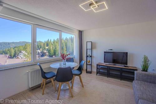 a living room with a table and chairs and a television at Hotel Central Vlasic in Vlasic