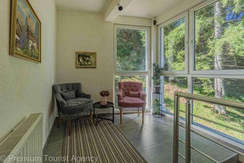 a living room with two chairs and large windows at Hotel Central Vlasic in Vlasic