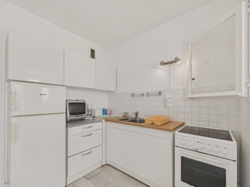 une cuisine blanche avec un évier et un micro-ondes dans l'établissement Vue mer - Appartement pour 2 adultes 2 enfants, à Les Sables-dʼOlonne