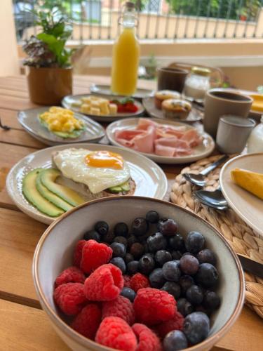 a table with a bowl of fruit and plates of breakfast foods at Le Camere Pietrasantine - Centro Storico in Pietrasanta