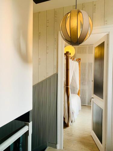 - un couloir avec une chambre dotée d'un lit et d'un lustre dans l'établissement Charmante maison au calme avec jardin à 5mn de île de Ré, à La Rochelle