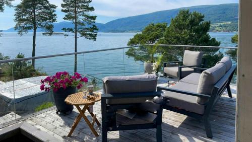 a balcony with chairs and a table and a view of the water at Seaside Cabin With Private Pier In Eidsvåg in Eidsvåg