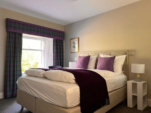 a bedroom with a large bed with purple pillows at Kilfinan Hotel in Kilfinan