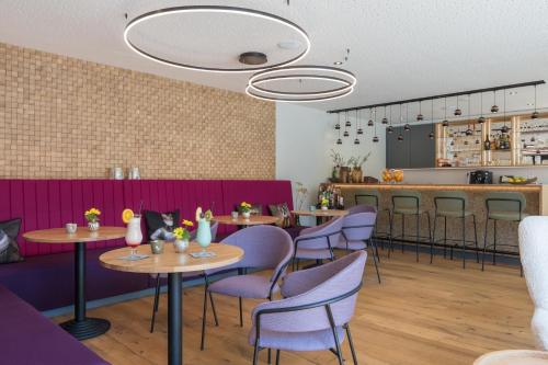 a restaurant with purple chairs and tables and a counter at Hotel Chrysantihof in Bad Birnbach