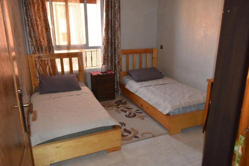 two beds in a small room with a window at Marrakech Sakan Annakhil im6 n31 in Marrakesh