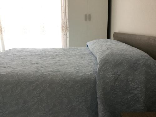 a bedroom with a bed with a gray comforter and a window at Hotel Bragozzo in Sottomarina