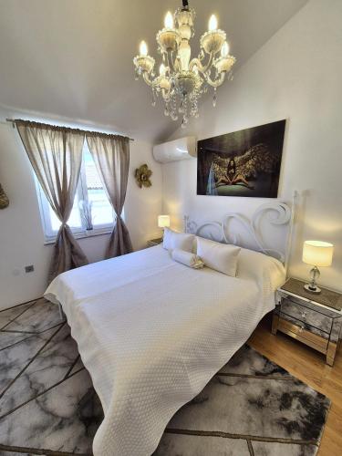 a bedroom with a large white bed and a chandelier at Apartment Sonja in Klimno