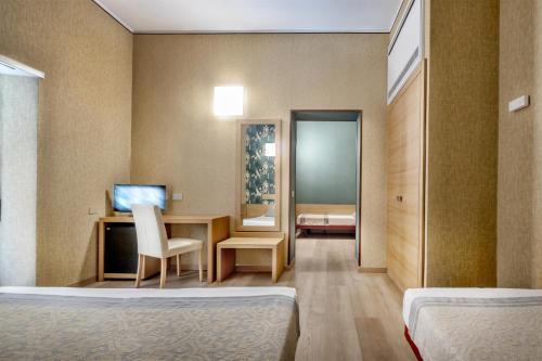 a room with two beds and a desk with a computer at Hotel Italia in Cagliari
