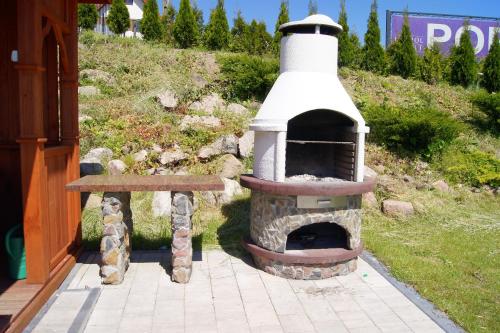 a outdoor oven with a bench next to a building at Ośrodek Dalpol in Prażmowo