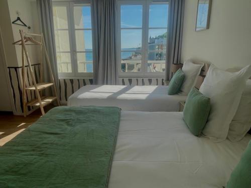 two beds in a hotel room with a view of the ocean at Hôtel De La Marine in Arromanches-les-Bains