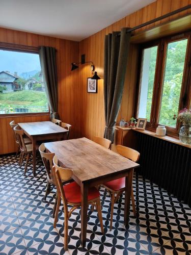 a dining room with two tables and chairs and windows at Le Bellacha in La Léchère