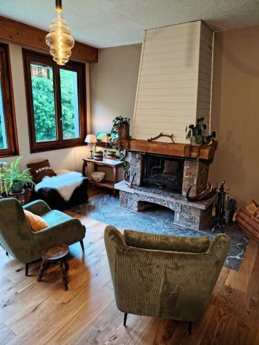 a living room with a fireplace and chairs at Le Bellacha in La Léchère