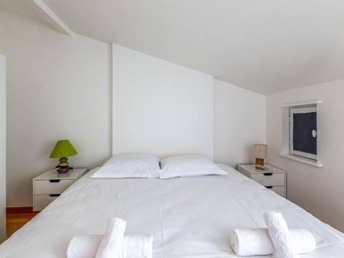 - une chambre blanche avec un grand lit blanc et 2 tables de chevet dans l'établissement Au coeur de ville, appartement t3 en duplex, à La Rochelle