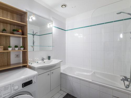 La salle de bains blanche est pourvue d'un lavabo et d'un lave-linge. dans l'établissement Au coeur de ville, appartement t3 en duplex, à La Rochelle