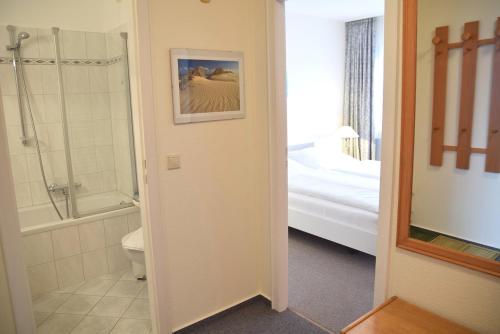 ein Bad mit einer Dusche, einem WC und einem Bett in der Unterkunft Gemütliches 2-Zimmer-Appartement mit Balkon. in Westerland
