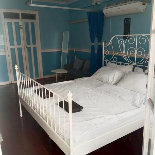 a bedroom with a white bed with a blue wall at Aran hostel&Cafe Ngamwongwan in Ban Bang Khen (1)